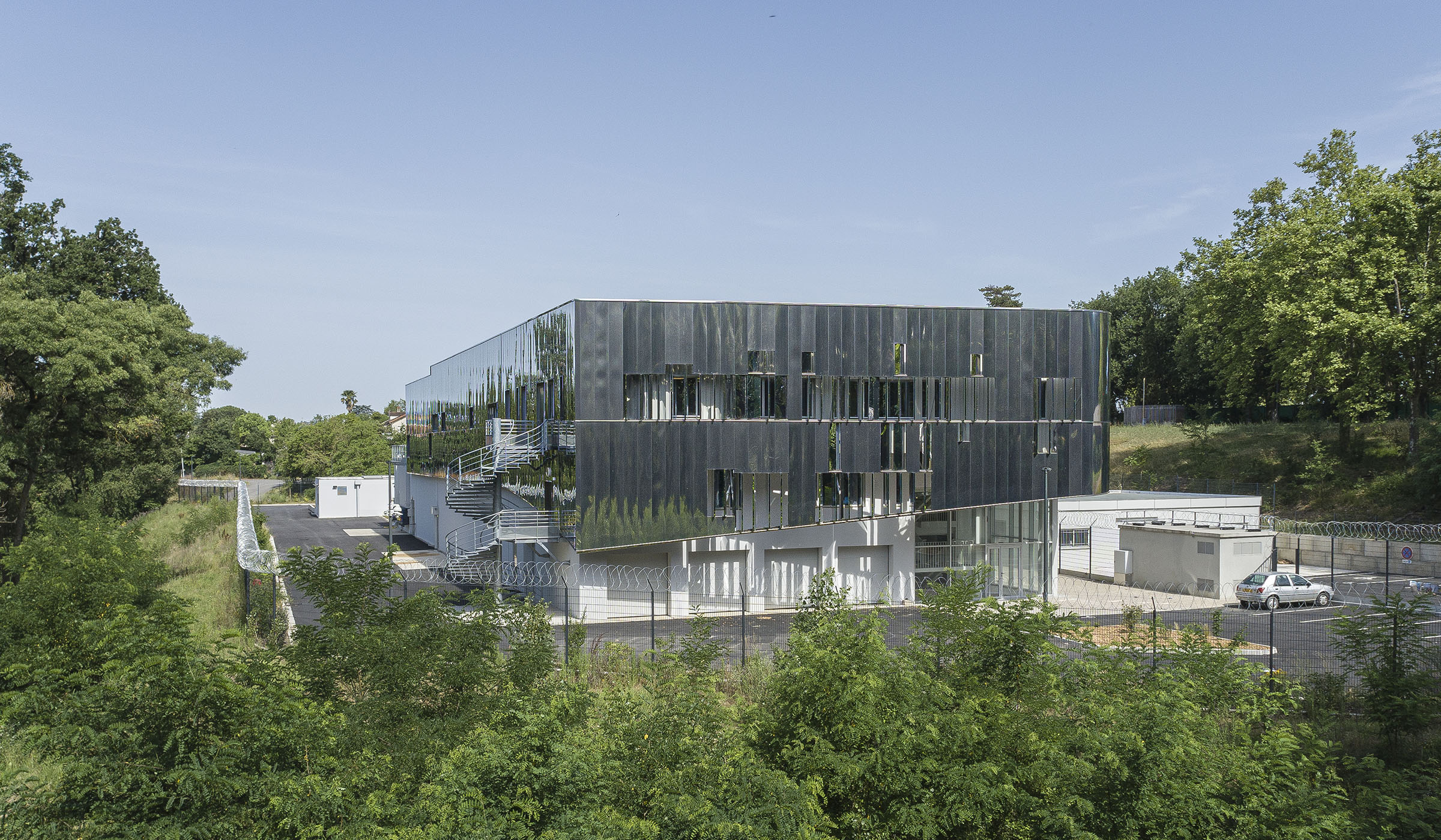 Photographie recadré vue drone depuis l'espace arboré, végétation entourant le bâtiment miroir