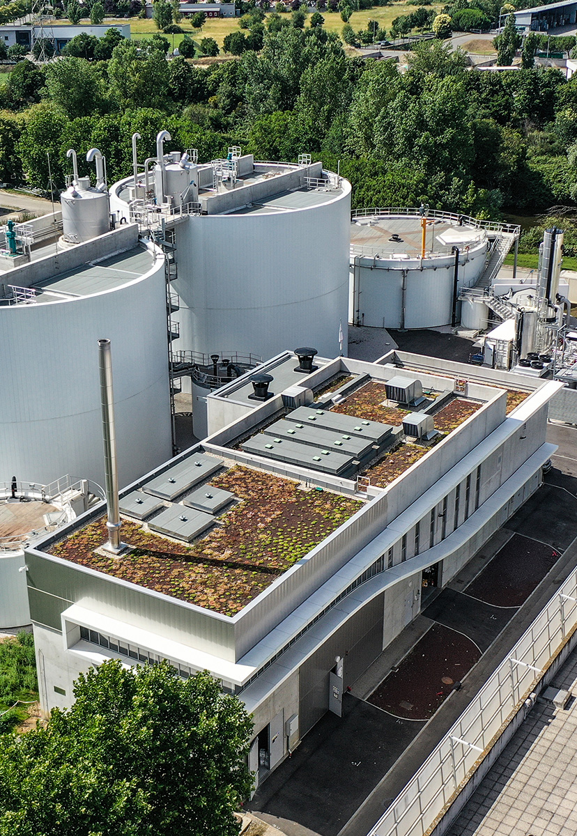 La toiture végétalisé du bâtiment principal de méthanisation à Toulouse Photographie drône du bâtiment principale qui gère la méthanisation à Ginestou Toulouse Métropole, bâtiment rectangulaire béton avec soubassement béton et brise soleil horizontale blanc sur la longueur de la partie vitrée