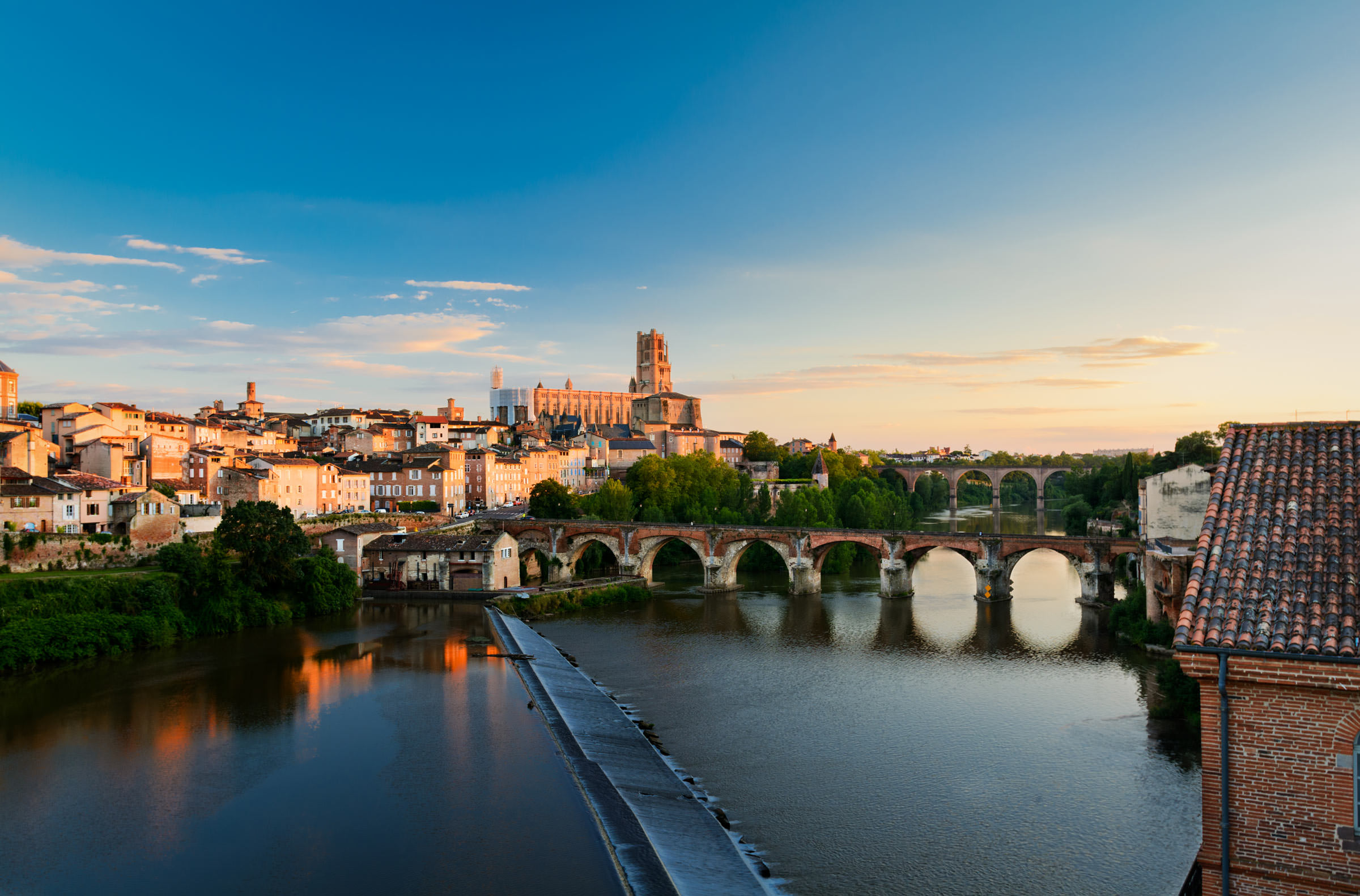 Photographie du levé de soleil sur la ville d'Albi depuis le Tarn, cathédrale d'Albi au centre