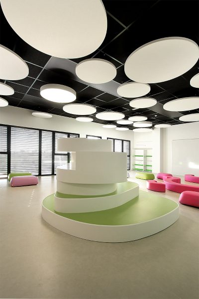 Photographie verticale de l'intérieure d'une salle de jeux avec pleins de modules colorés, plafond noir avec des grands ronds blanc et certains s'allument