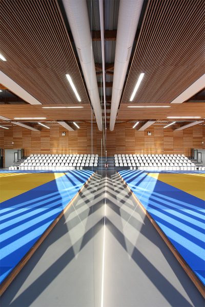 Photographie vue miroir de l'intérieur du gymnase de Buchelay, intérieur bois et tatamis bleu et jaune