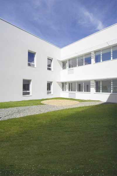 Photographie d'un angle entre deux facades blanches, depuis le patio intérieur