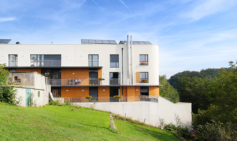 Photographie verticale depuis les jardins du bâtiment, panneaux photovoltaiques sur le toit, des coursives permettent aux chambres de communiquer