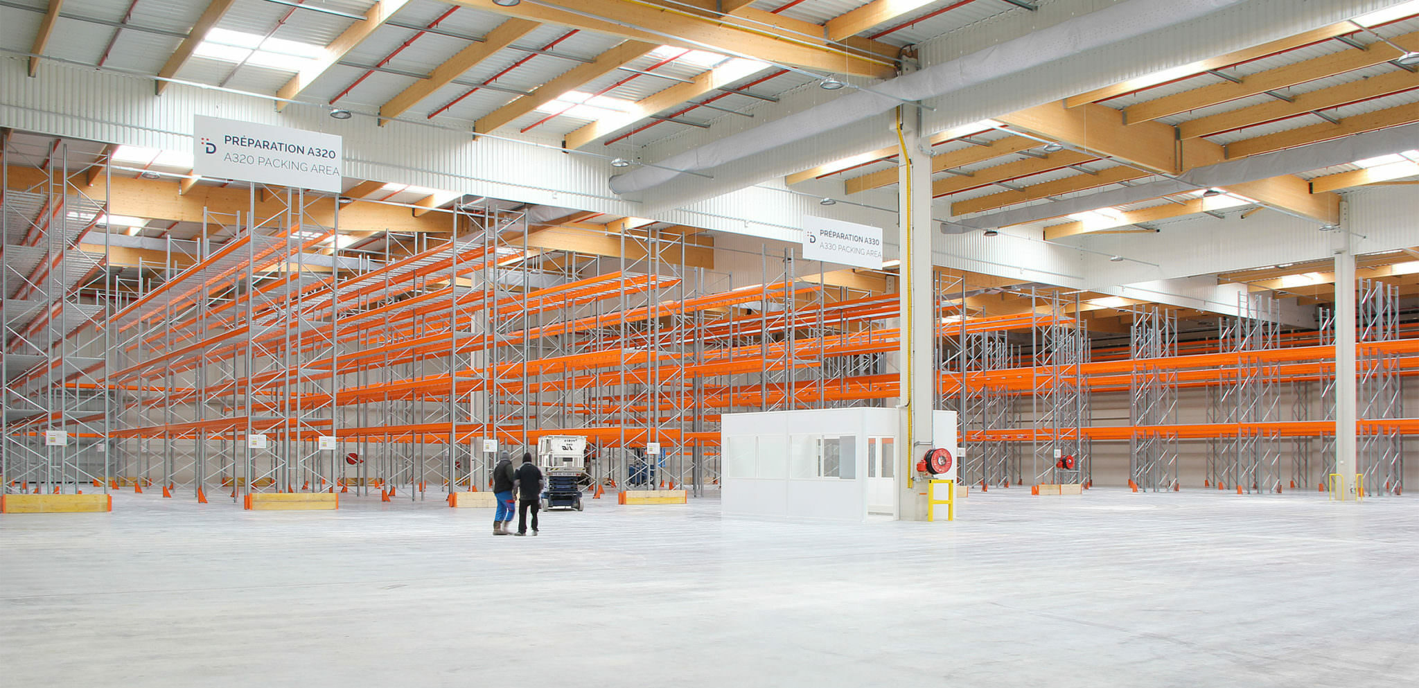 Photographie du hangar de stockage à sa livraison, les espaces des rangements vide nous laisse voir la grandeur du volume, bardage blanc, skydome et poutres bois