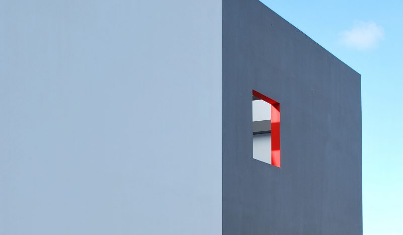 Photographie d'un détail de la façade grise avec ouverture et contour rouge