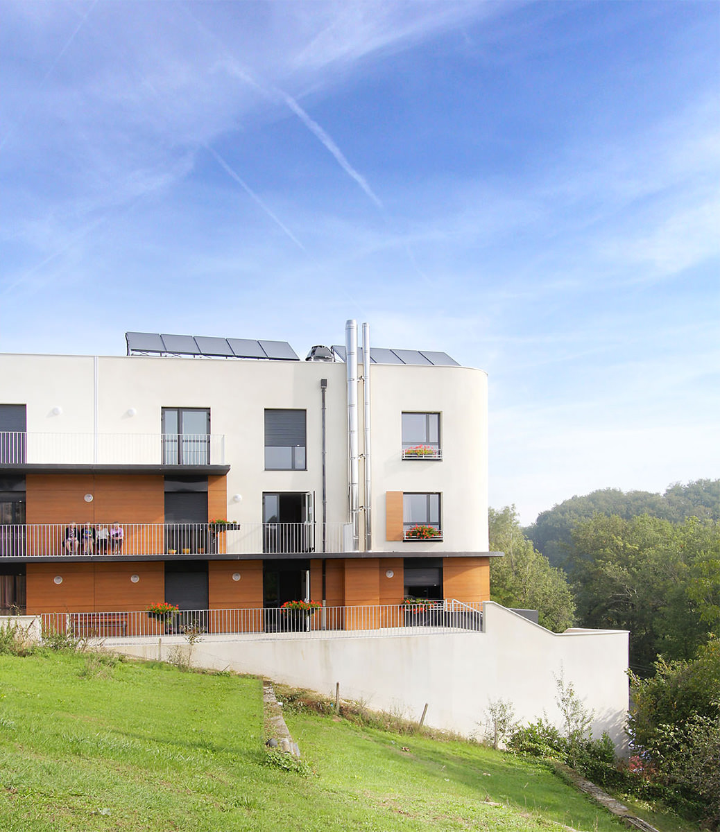 Photographie verticale depuis les jardins du bâtiment, panneaux photovoltaiques sur le toit, des coursives permettent aux chambres de communiquer