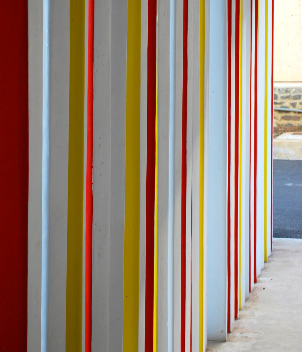 Photographie d'un détail de ventelles en béton de trois nuances, rouge jaune blanc