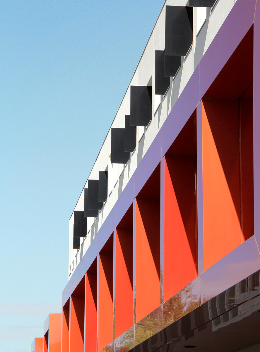 Photographie en contre-plongé d'un détails de la façade l'internat, des boîtes rouges brise-soleil sur certaines fenêtres