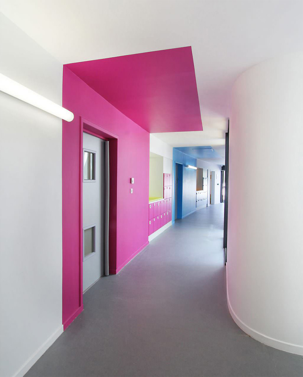 Photographie d'intérieure du couloir blanc avec des signalétiques de formes et de couleurs sur les murs et plafonds