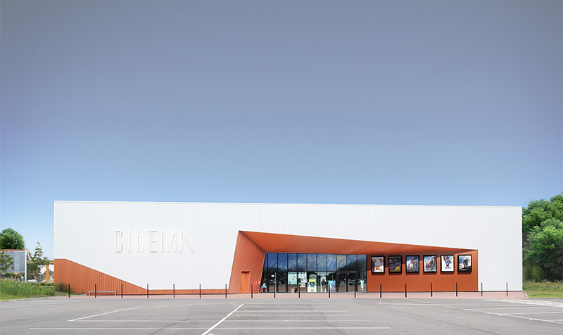 Photographie face à l'entrée du cinéma de Mont-de-Marsan, façade blanche et renfoncement de l'entrée couleur ocre orangé, entrée vitrée, parking vide