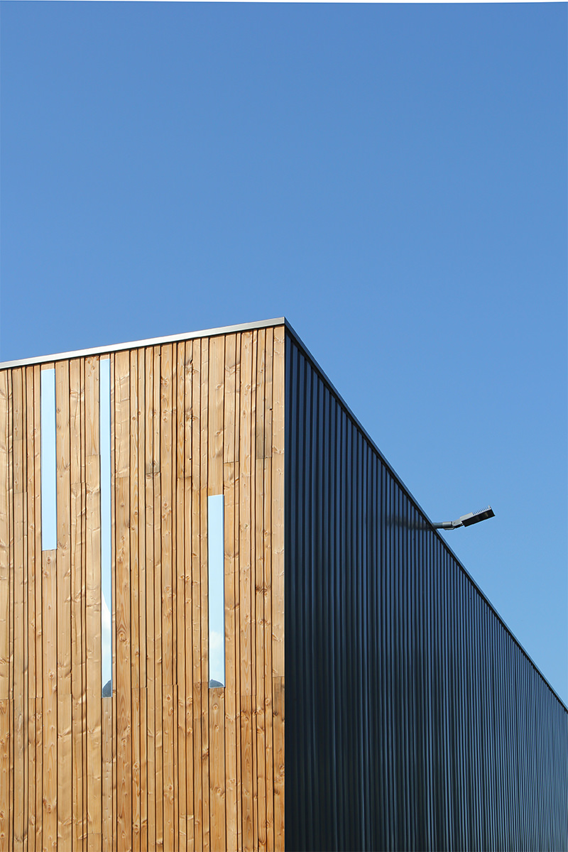 Photographie d'un détail de la façade bois et de quelques lattes de métal