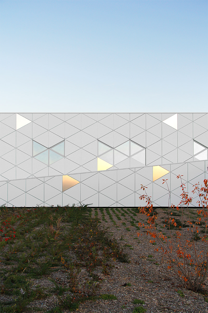 Photographie face à une façade blanche et quelques facettes triangles reflétent le soleil