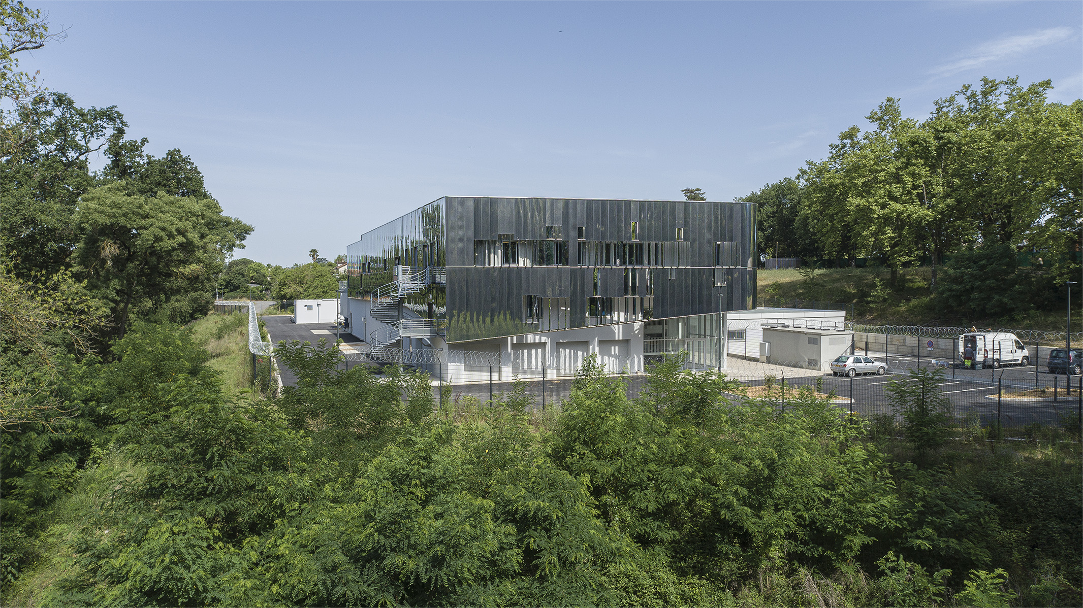 Photographie vue drone depuis l'espace arboré, végétation entourant le bâtiment miroir