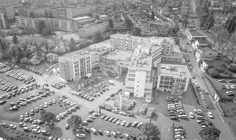 Photographie drone niveau de gris de la Clinique Claude Bernard à Albi, bâtiment en forme de H avec grand parking devant