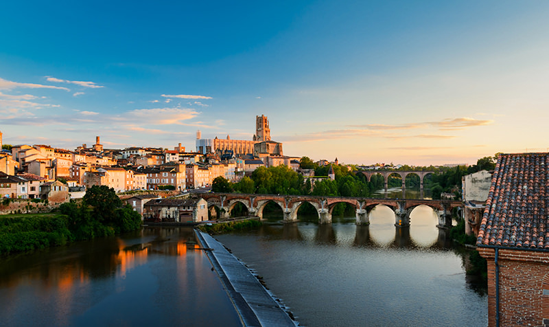 Photographie du levé de soleil sur la ville d'Albi depuis le Tarn, cathédrale d'Albi au centre