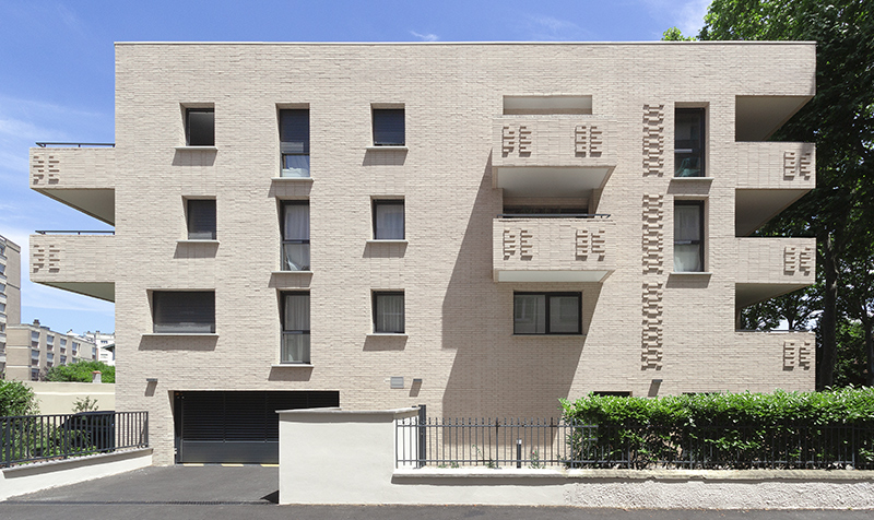 Photographie en face de la façade principale du projet Crampel, alignement des balcons et motifs de briquettes