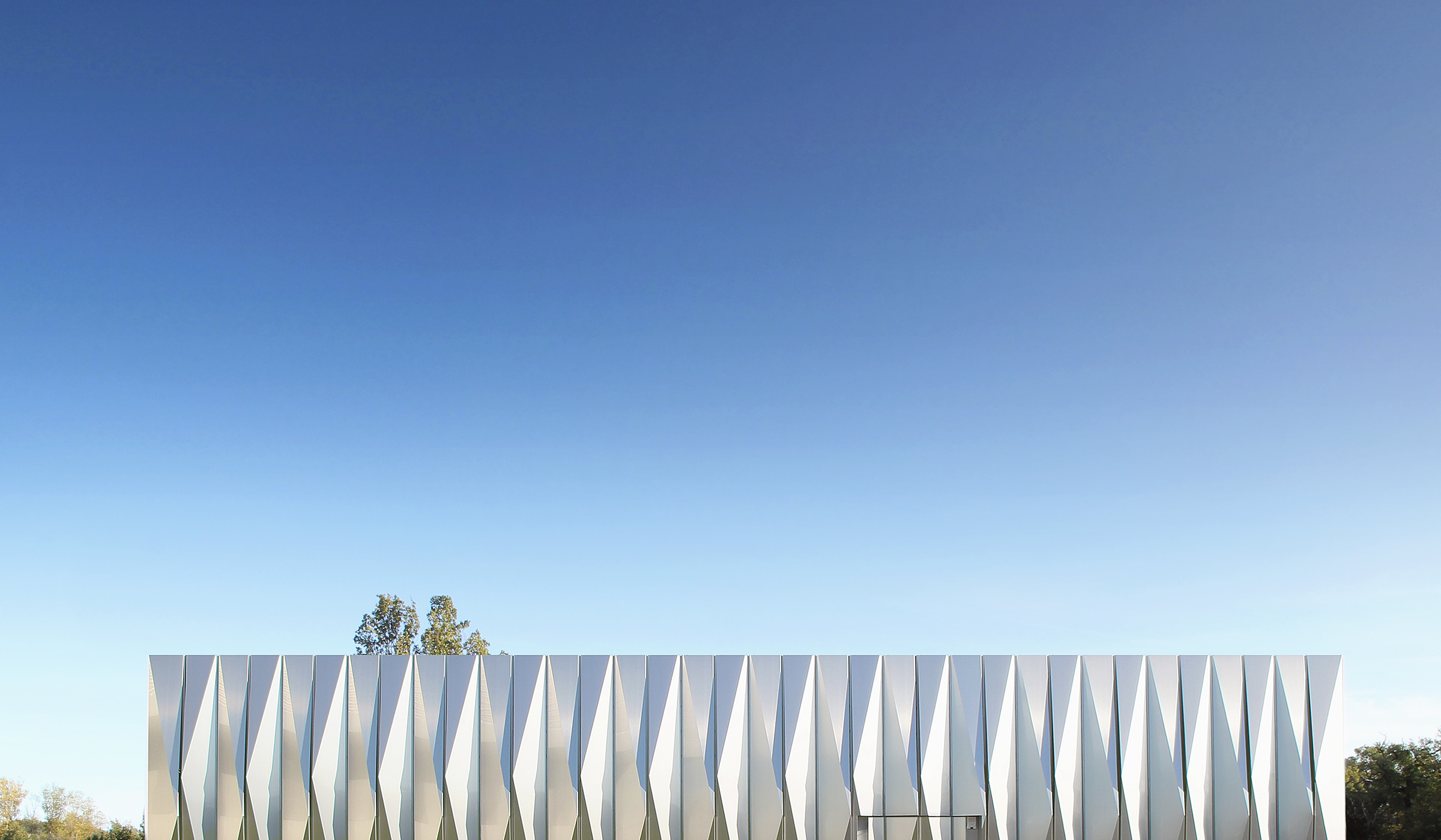 Photographie du haut du bardage du Datacenter reflétant le ciel bleu