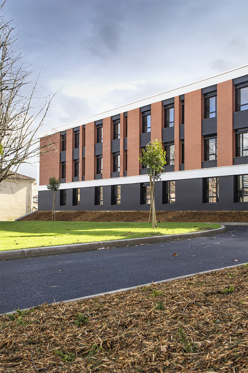 Photographie verticale d'une partie de la façade principale, briquettes et soubassement anthracite