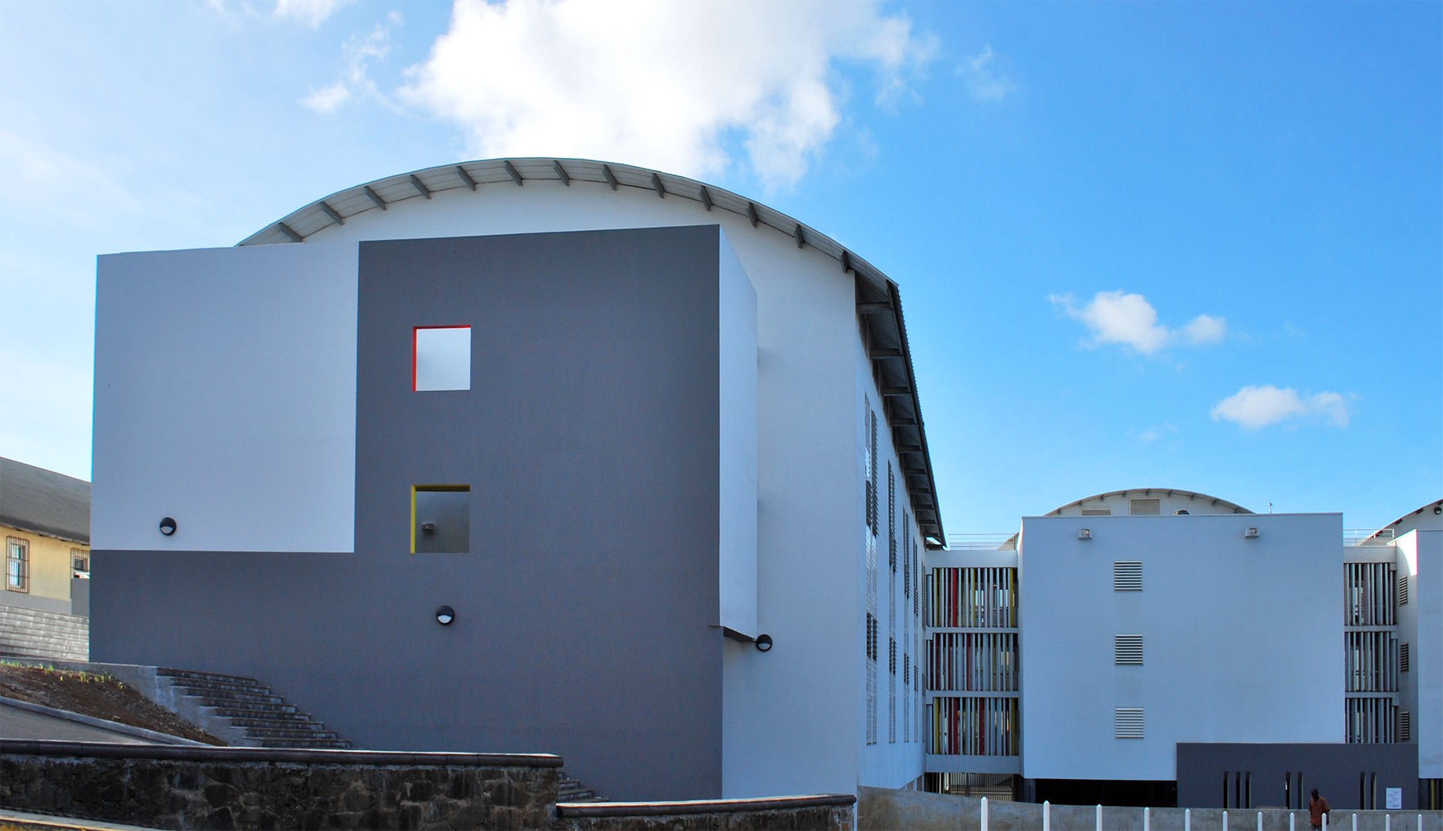 Photographie de l'ensemble du bâtiment, avec les ouvertures et ventelles colorées et les toitures courbes