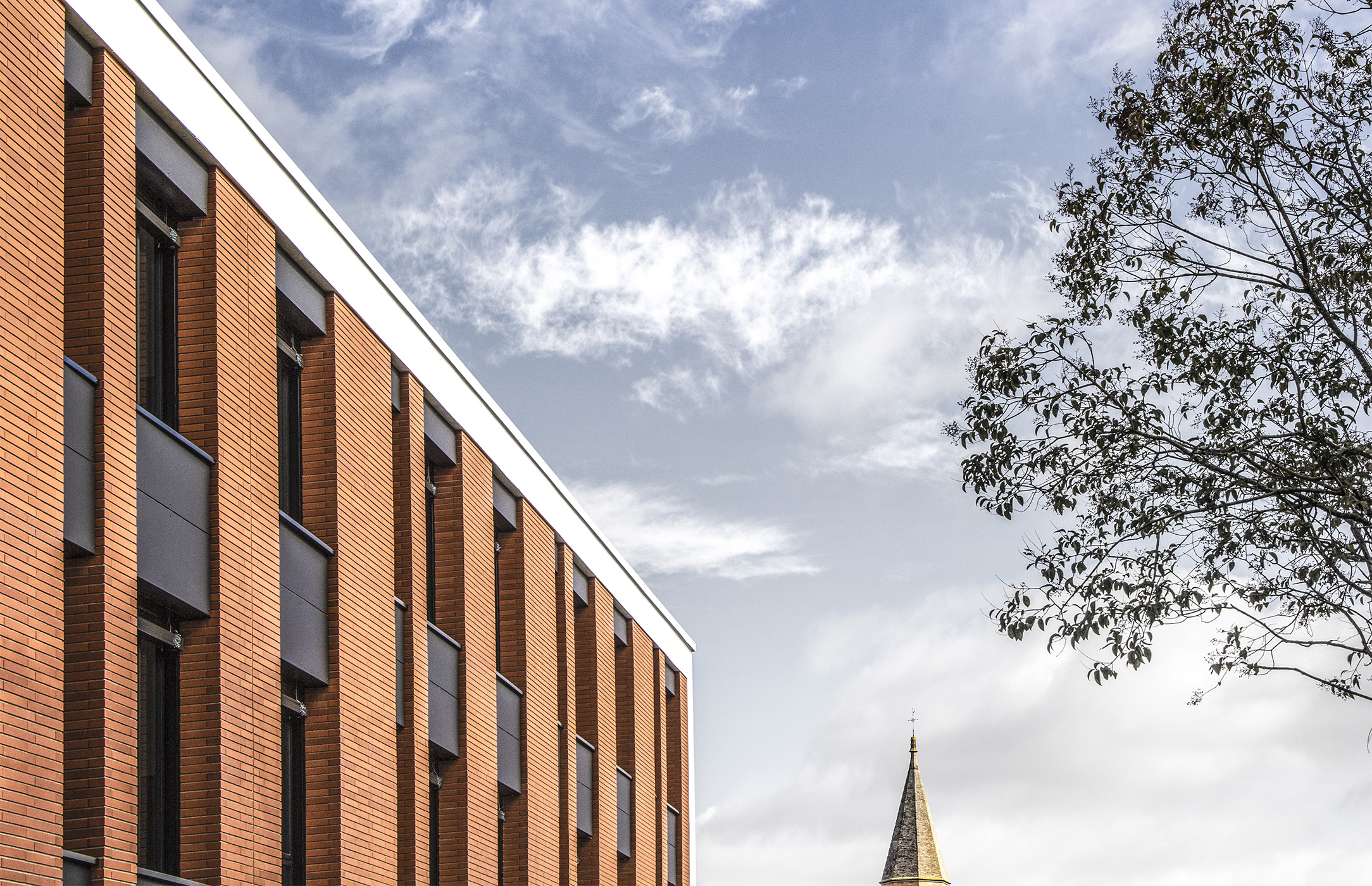 Photographie zoomé de biais de la façade en briquette de l'Hôpital de Gaillac, ciel clair nuageux