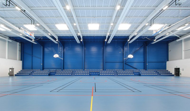 Photographie de l'intérieur du gymnase blanc de Lescure d’Albigeois, face aux gradins zone coloré en bleue