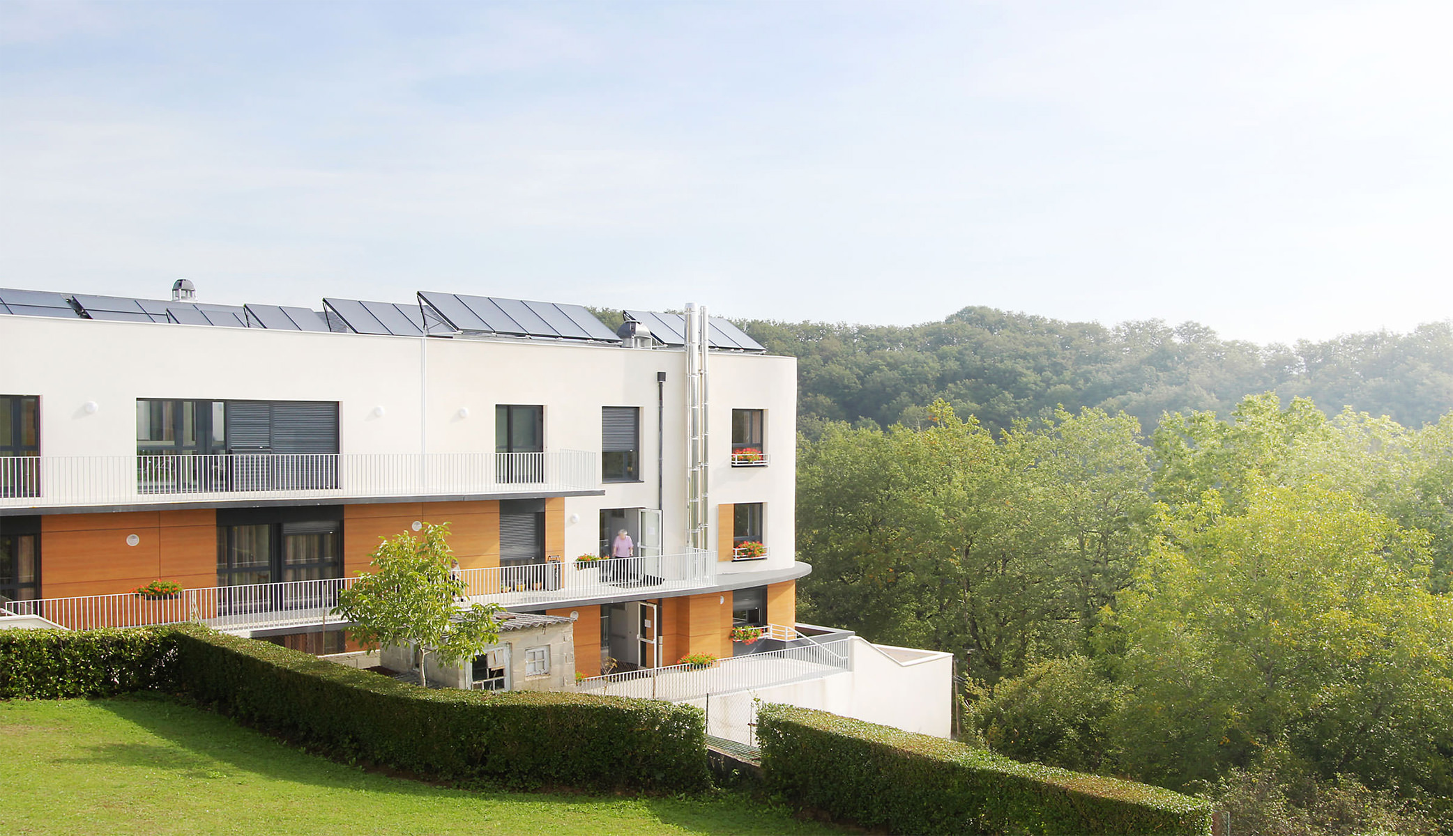 Photographie de biais depuis le jardin sur les hauteur, le bâtiment donne sur la fôret
