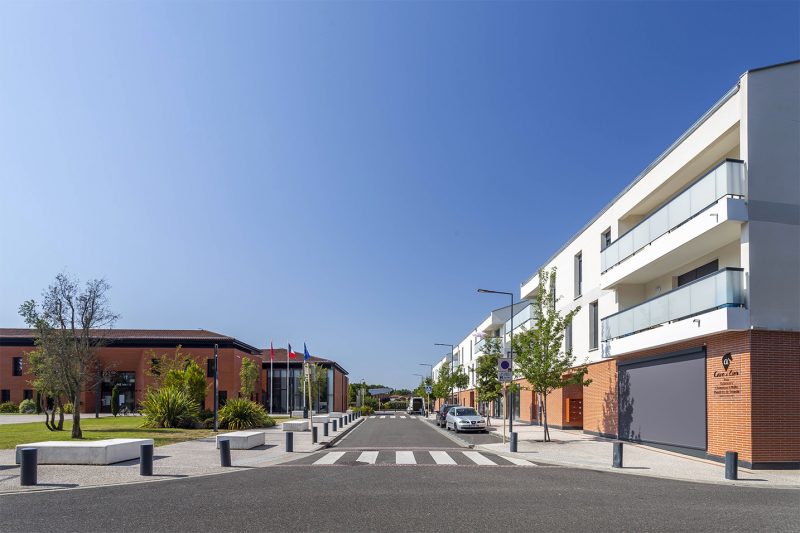 Photographie face à la rue qui sépare la mairie et les logements
