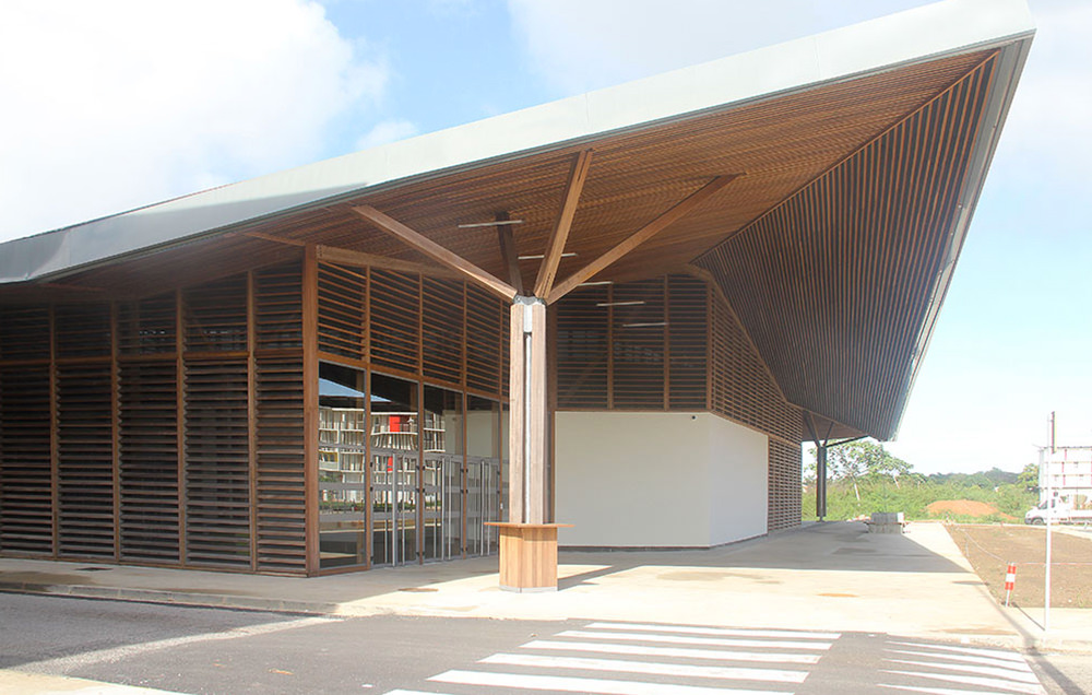 Photographie de l'entrée du restaurant avec le auvent en lames de bois et des brises-soleil bois en façades