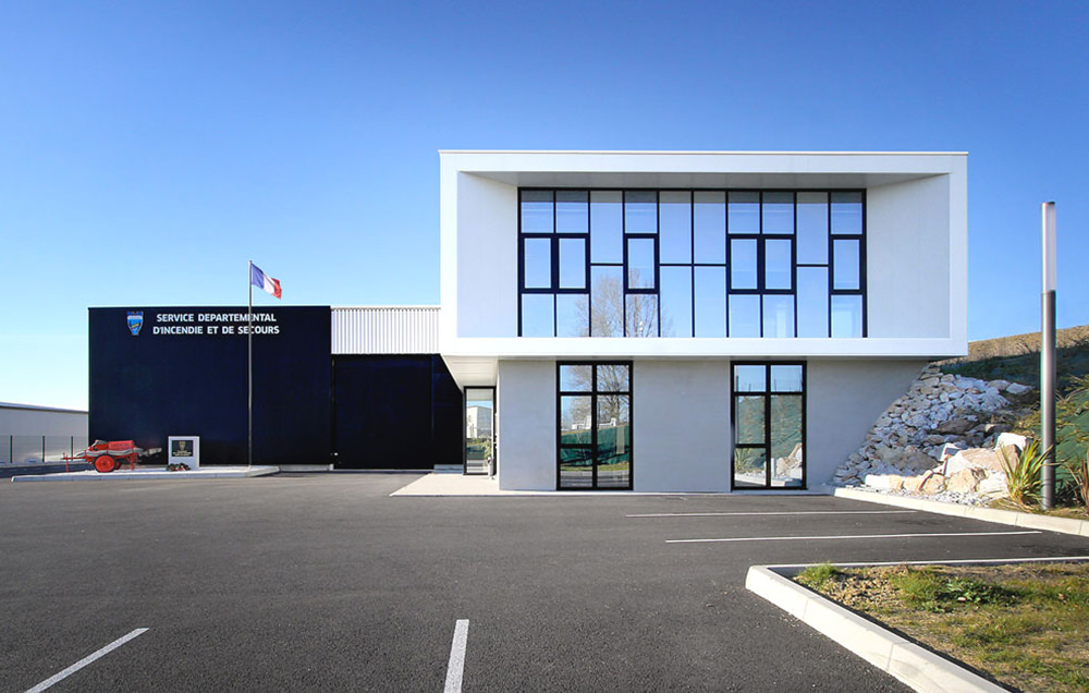 Photographie face au bâtiment blanc vitrée avec baie vitrée sur toute la longeur encastré dans la facade