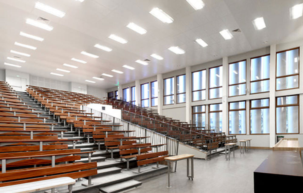 Photographie de l'amphithéâtre blanc avec les tables en bois et vitrage sur toute la hauteur