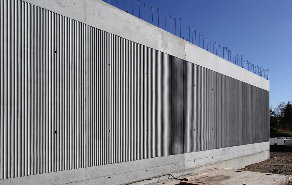 Photographie d'un mur béton gris matricés avec des lignes verticales cannelées