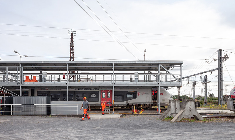 Photographie de la passerelle sur le côté avec un train et des techniciens en train de travailler