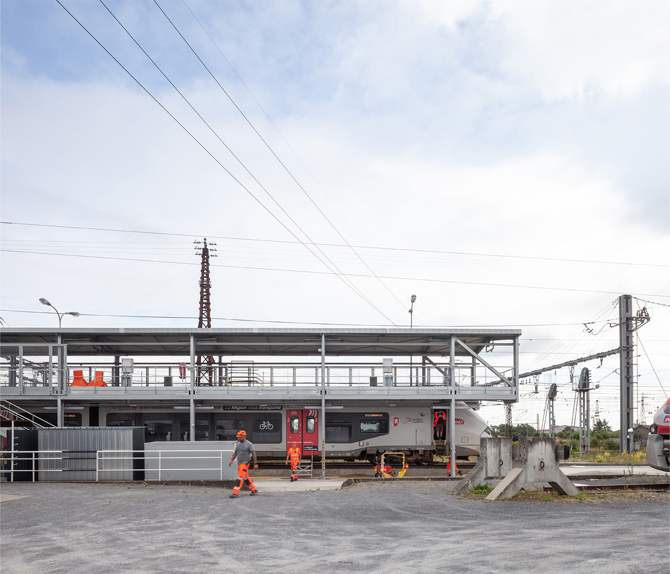 Photographie de la passerelle sur le côté avec un train et des techniciens en train de travailler