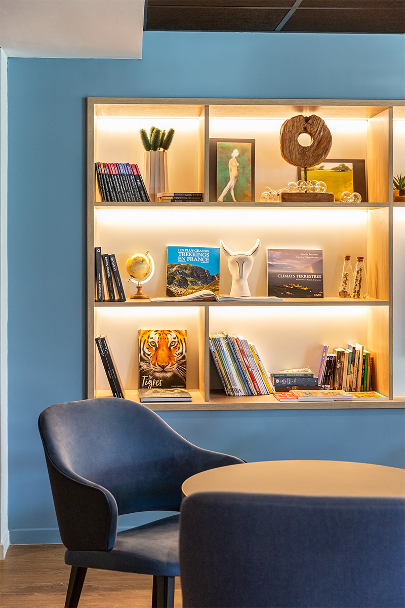 Photographie cadrée sur un fauteuil du hall d'accueil et la bibliothèque lumineuse en arrière plan