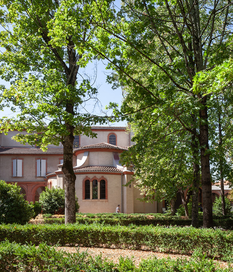 Photographie depuis le jardin vue sur le diocèse d'Albi en arrière plan entre les grands arbres et plusieurs rangé de haies et d'arbustes sur le côté